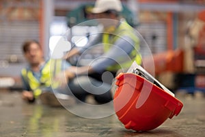 Red Hard Hat with Blurred Injured Factory Workers as a Background