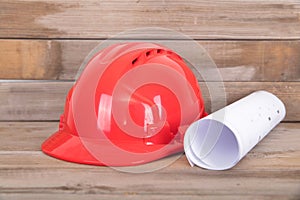 Red hard hat and a roll of drawings on the table