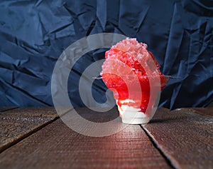 Red Hawaiian Shave ice, Shaved ice or snow cone dessert in a clear flower cup against a black background. photo