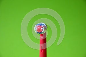 Red head for an electric toothbrush. Green background.