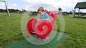 Red headed boy with a blue t-shirt having fun having fun in Playpark on a sunny day