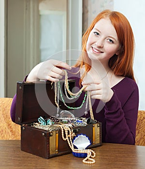 Red-headed girl looks jewelry in treasure chest