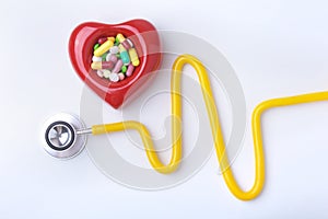 Red heart, asorted pils and a stethoscope on white background.