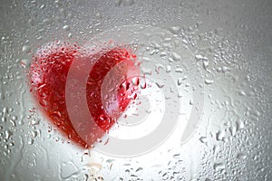 Red heart behind a wet window