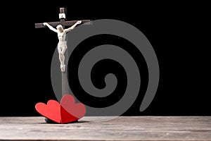 The red heart on black black background including cross beside the heart. The cross is the symbol of Christian religion. God love