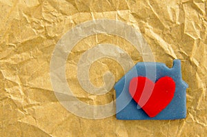 Red heart in a blue lodge from plasticine on the rumpled made old paper