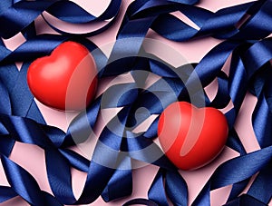 Red heart and blue silk curled ribbon on a pink background, valentine`s day