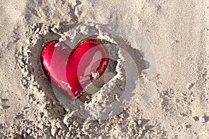 Red heart buried in the sand