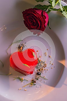 Red heart cake served on white plate on valentines day with roses, romantic evening and gift