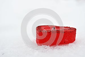 Red heart candle in the snow, a gift for loved ones