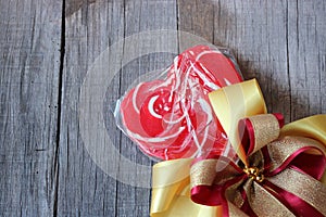 Red heart candy with ribbon on old wooden board background. Valentine`s day concept.