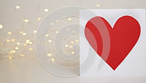 Red heart card on bokeh background with hearts. Valentine's day celebration or love concept. Copy space