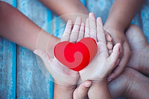 Red heart in child and parent hands with love and harmony