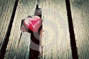 Red heart in crack of wooden plank. Symbol of love