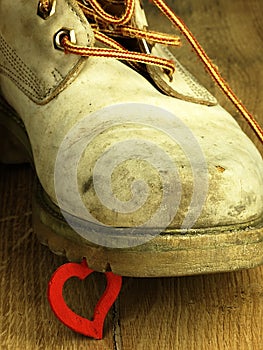 Red heart crushed by a heavy, old military boot.