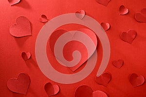 Red heart cutouts of various sizes spread over red background