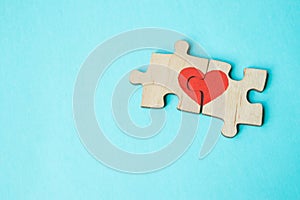 Red heart is drawn on the pieces of the wooden puzzle lying next to each other on blue background. Love concept. St. Valentine day