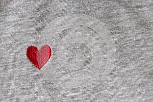 Red heart embroidered with threads on gray fabric background. Close-up, macro, copy space, flat lay. March 8, February 14,