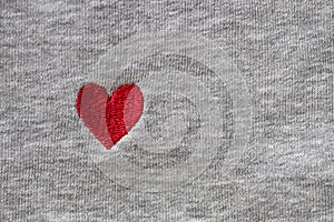 Red heart embroidered with threads on gray fabric background. Close-up, macro, copy space, flat lay. March 8, February 14,