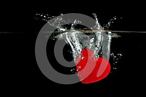 Red heart falling on water splashing.