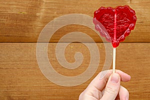 Red heart in female hand on brown background