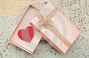 Red heart in gift box on grunge wood background