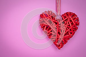 Red heart hand-made on a rope on pink background. Romantic gift card on valentines day. Symbol of love. Copy, text space. Holiday