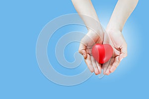 Red heart in hand women on blue background. cardiology symbol, valentine gift, love and health concept.