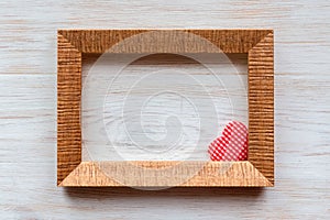 Red heart of handmade striped fabric in wooden frame corner on vintage white painted wooden background