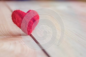 red heart handmade of wool on wooden background, a symbol of love, bright sun