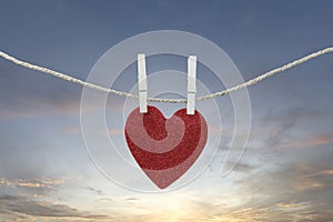 Red heart hanging on a hemp rope on the morning sky background