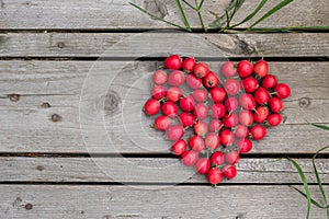 Red heart of hawthorn berries on a wooden background