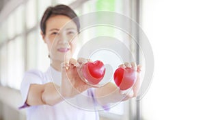 Red heart held by smiling female nurse`s hand, representing giving effort high quality service mind to patient. Professional, Spe photo