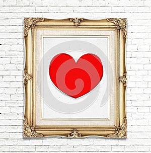 Red heart icon in golden vintage photo frame on white brick wall