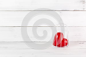 Red Heart inside Bird Cage on white wood background. Freedom Love with Copy Space