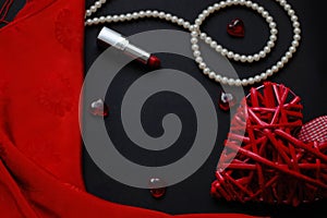 Red heart and lipstick, on a black background, a string of white pearls and a silk handkerchief