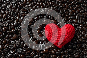 Red heart on a lot of roasted coffee beans background. Strong black espresso, Grains of coffee background, texture