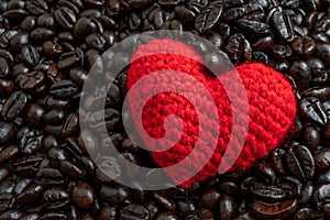 Red heart on a lot of roasted coffee beans background. Strong black espresso, Grains of coffee background, texture