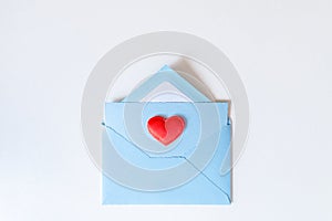Red heart lying on a blue envelope on white background