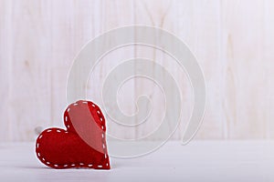 Red heart made of handmade felt, on a white wooden table, Concept, banner, save space