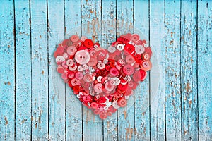 Red heart of many buttons on a blue wooden background