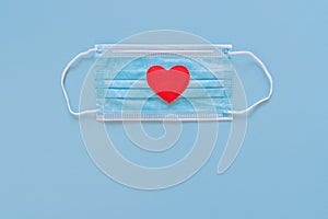 Red heart on medical protective face mask with red hearts on blue background
