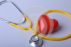 Red heart and a medical stethoscope on desk