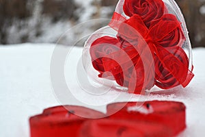 Red heart in the melted snow. three red candles in the shape of a heart.