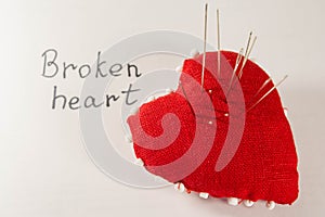 Red heart with needles in it on white background and inscription