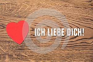 Red heart post-it and the text `Ich liebe dich` on a wooden background. Translation: `I love you`