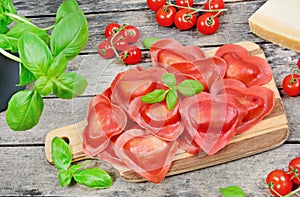 Red heart ravioli with tomato, mozzarella and basil on a vintage table