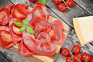 Red heart ravioli with tomato, mozzarella and basil on a vintage table