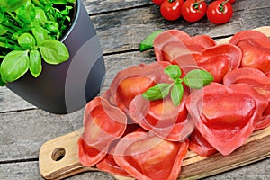 Red heart ravioli with tomato, mozzarella and basil on a wood background