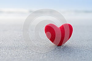 Red heart on the sand surface